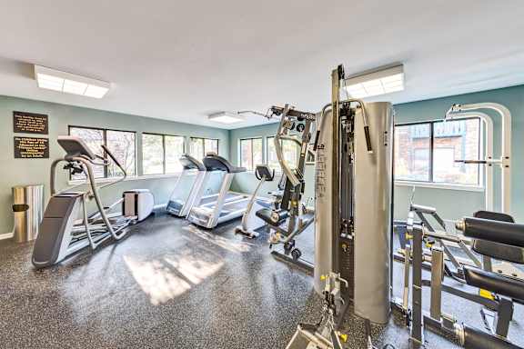 A gym with a variety of equipment including treadmills, weights, and exercise machines.