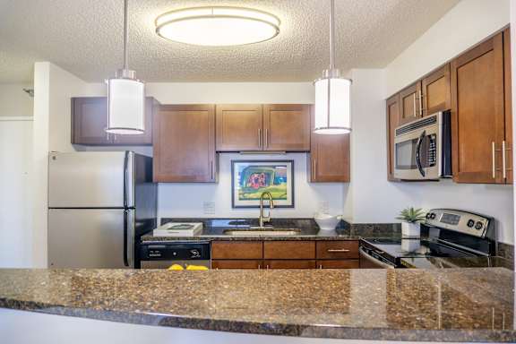 A kitchen with brown cabinets and granite countertops.
