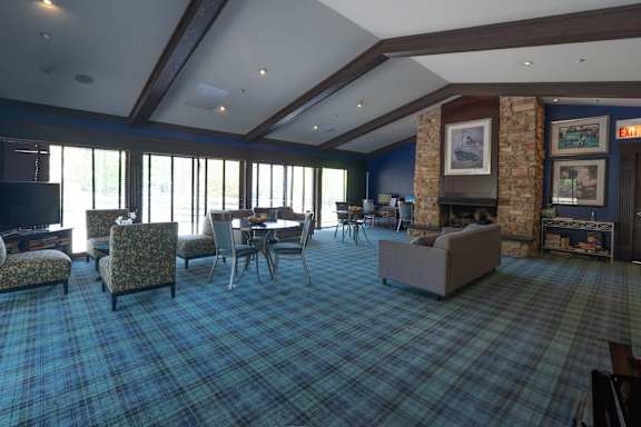 A room with a plaid carpet and a stone fireplace.