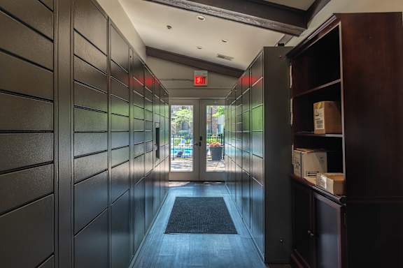 A hallway with a black door mat and a red exit sign.