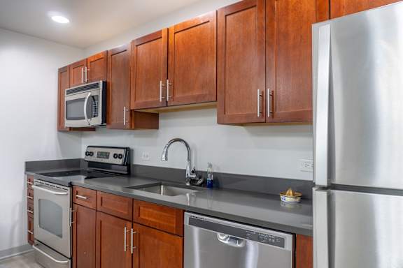 A kitchen with a stainless steel refrigerator, microwave, oven, and sink.