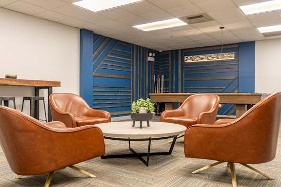 A conference room with a blue accent wall and brown leather chairs.