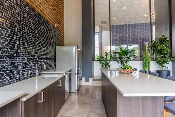 A kitchen with a white counter top and a black brick wall.