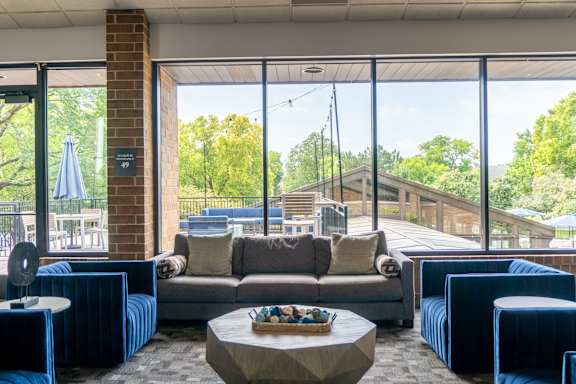 A living room with a brick column and a couch with a pillow on it.