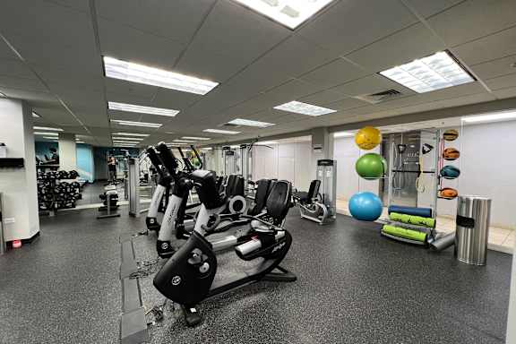 A gym with a variety of equipment including a treadmill, stationary bike, and weight machines.
