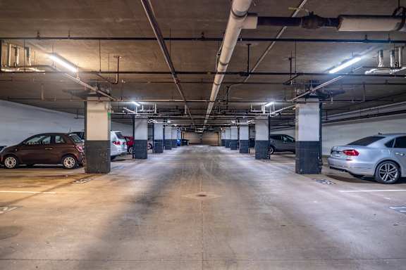A parking garage with cars parked on both sides of the aisle.