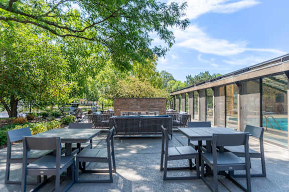A patio with a table and chairs is surrounded by trees.