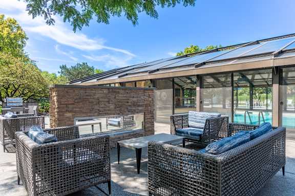 A patio with a table and chairs and a pool in the background.