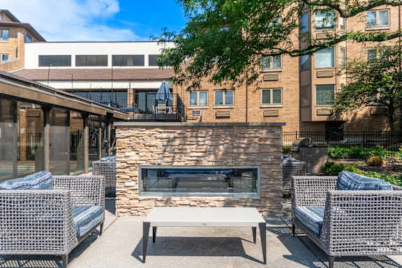 A patio with a stone fireplace and wicker chairs.
