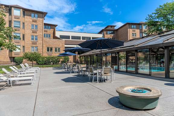 A sunny day at the poolside with chairs and umbrellas.