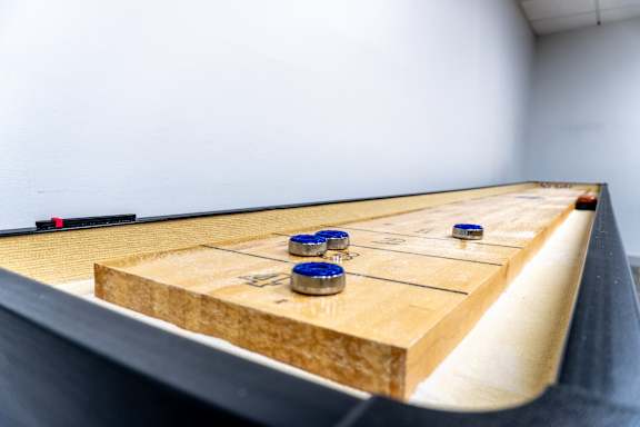 A shuffleboard table with blue pucks on it.