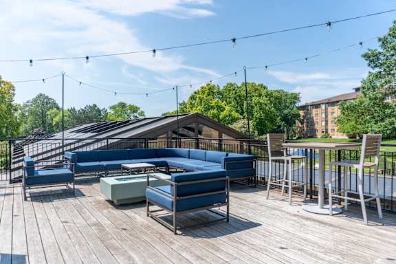 A wooden deck with blue couches and a table with chairs.