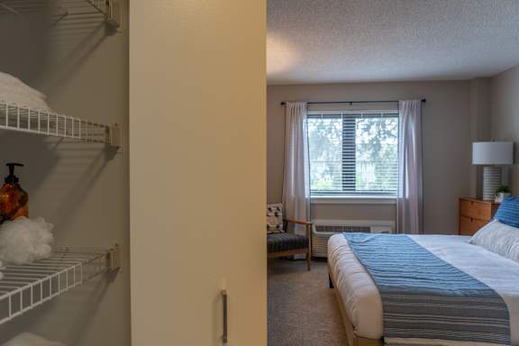 A bedroom with a bed, nightstand, and window with curtains.