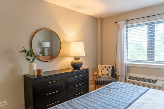 A bedroom with a bed, dresser, and window.
