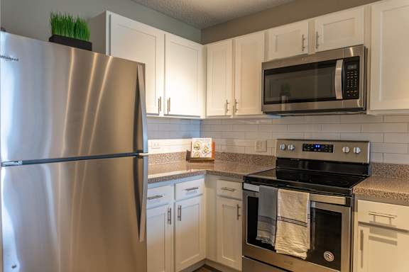 A kitchen with a stainless steel refrigerator, microwave, and oven.