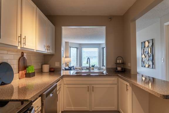 A kitchen with white cabinets and a granite countertop.