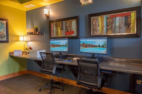 Two computer monitors are on a desk in an office.