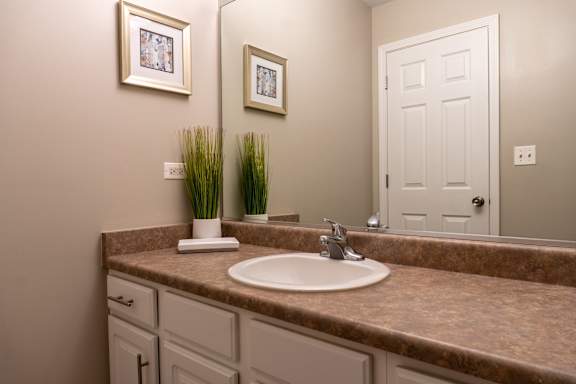 A bathroom with a brown granite countertop and a white sink.