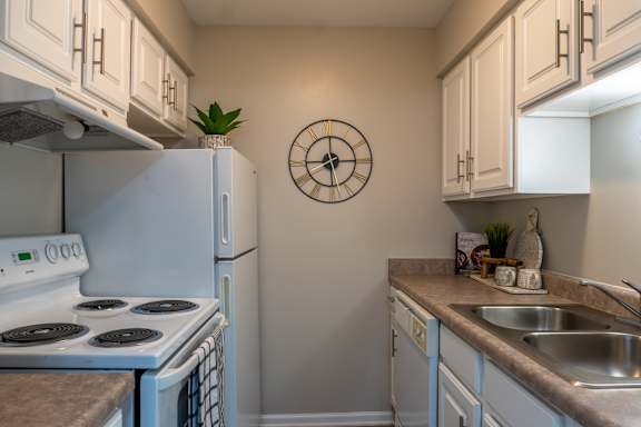 A white stove and oven in a kitchen with a clock on the wall.