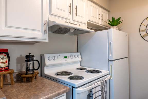 A white stove with a kettle on it in a kitchen.