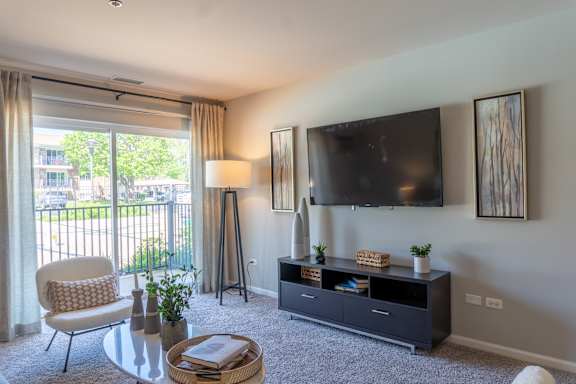 A living room with a flat screen TV mounted on the wall above a cabinet.