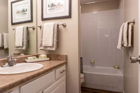 A bathroom with a sink, mirror, and towel rack.