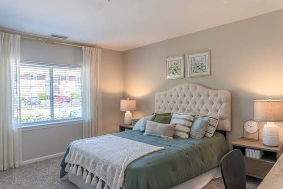 A bedroom with a large bed and a window with curtains.