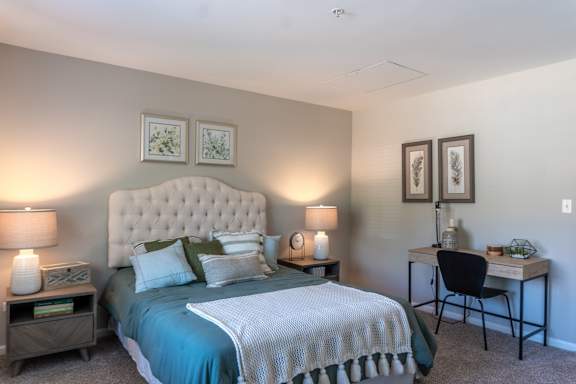 A bedroom with a large bed and a desk with a chair.
