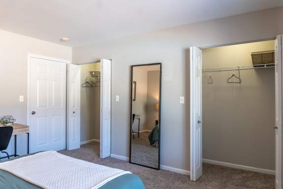 A bedroom with a bed, desk, and closet.