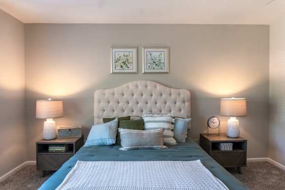 A bedroom with a large bed and two lamps.