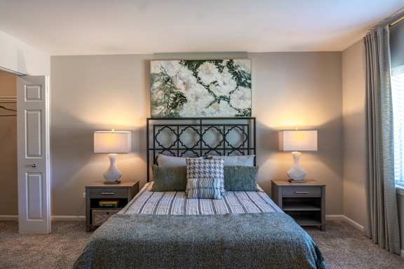 A bedroom with a large bed and two lamps.