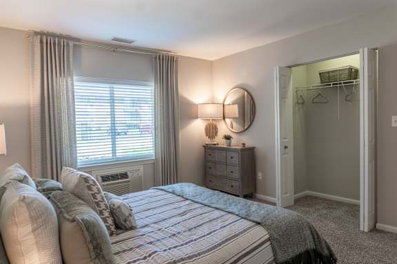 A bedroom with a bed, dresser, and window.