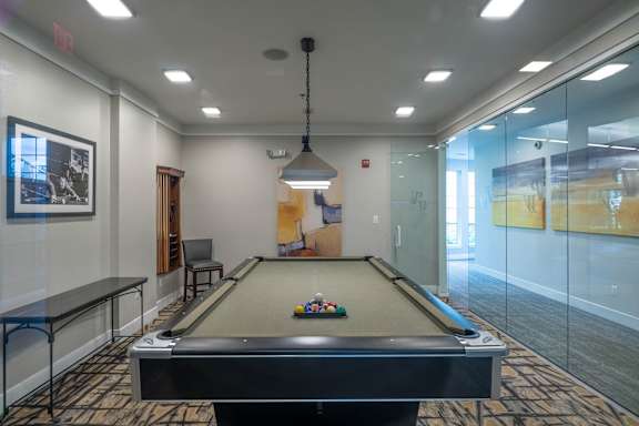 A pool table in a room with a glass wall.