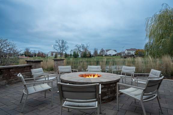 A fire pit surrounded by chairs on a patio.