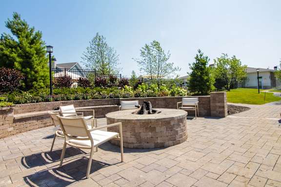 A patio with a fire pit and chairs.