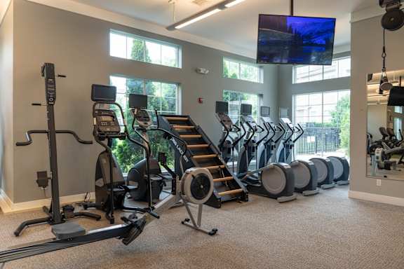 A gym with a row of treadmills and elliptical machines.
