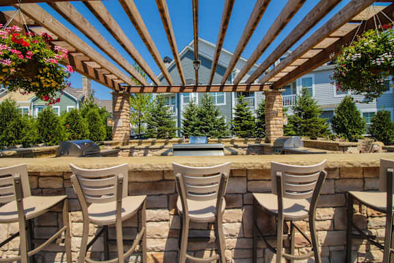 A patio with a bar and chairs under a wooden pergola.