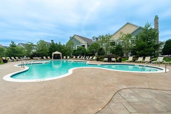 A large outdoor swimming pool with a white tile border and a white diving board.