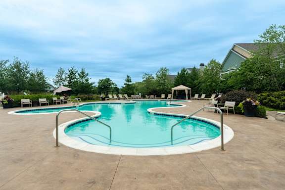 A large outdoor pool with a slide and a hot tub.