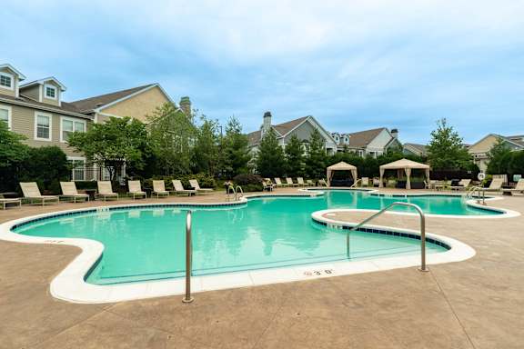 A large outdoor swimming pool surrounded by lounge chairs and umbrellas.