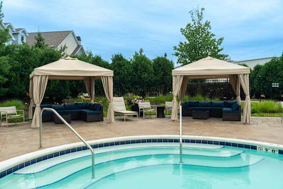 A pool with a canopy and chairs around it.