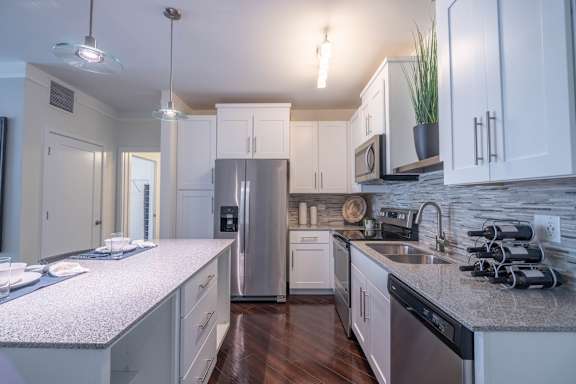 A kitchen with white cabinets and a granite countertop.