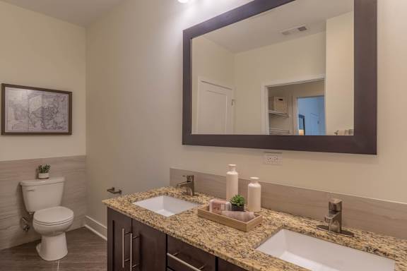 A bathroom with a toilet, sink, and mirror.