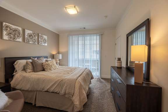 A bedroom with a large bed and a chair.