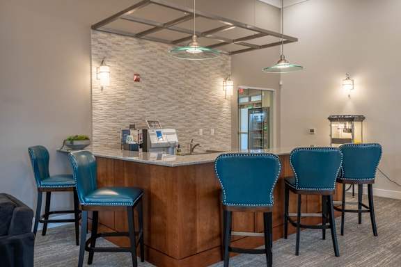 A bar area with blue chairs and a white brick wall.