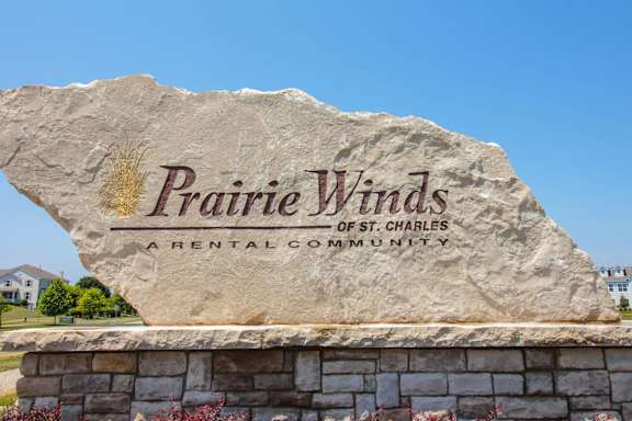 A large stone sign that says Prairie Winds in front of a house.