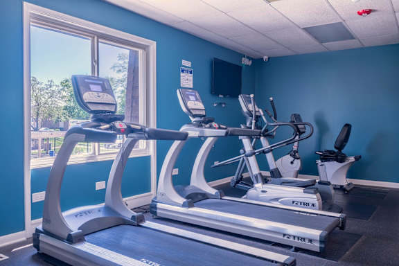 A gym with treadmills and a television.