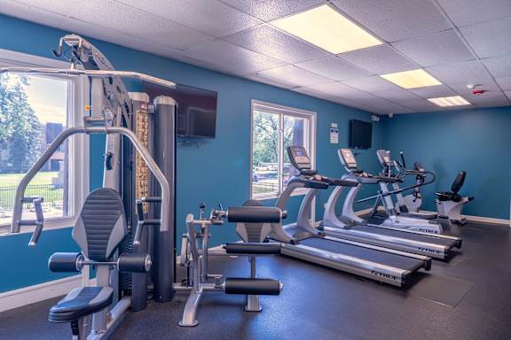 A gym with a variety of equipment including treadmills, weights, and exercise machines.
