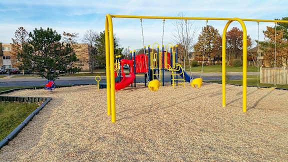A playground with a yellow swing set and a red slide.