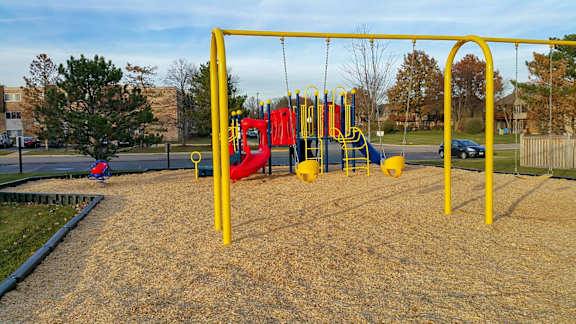 A playground with a yellow swing set and a red slide.
